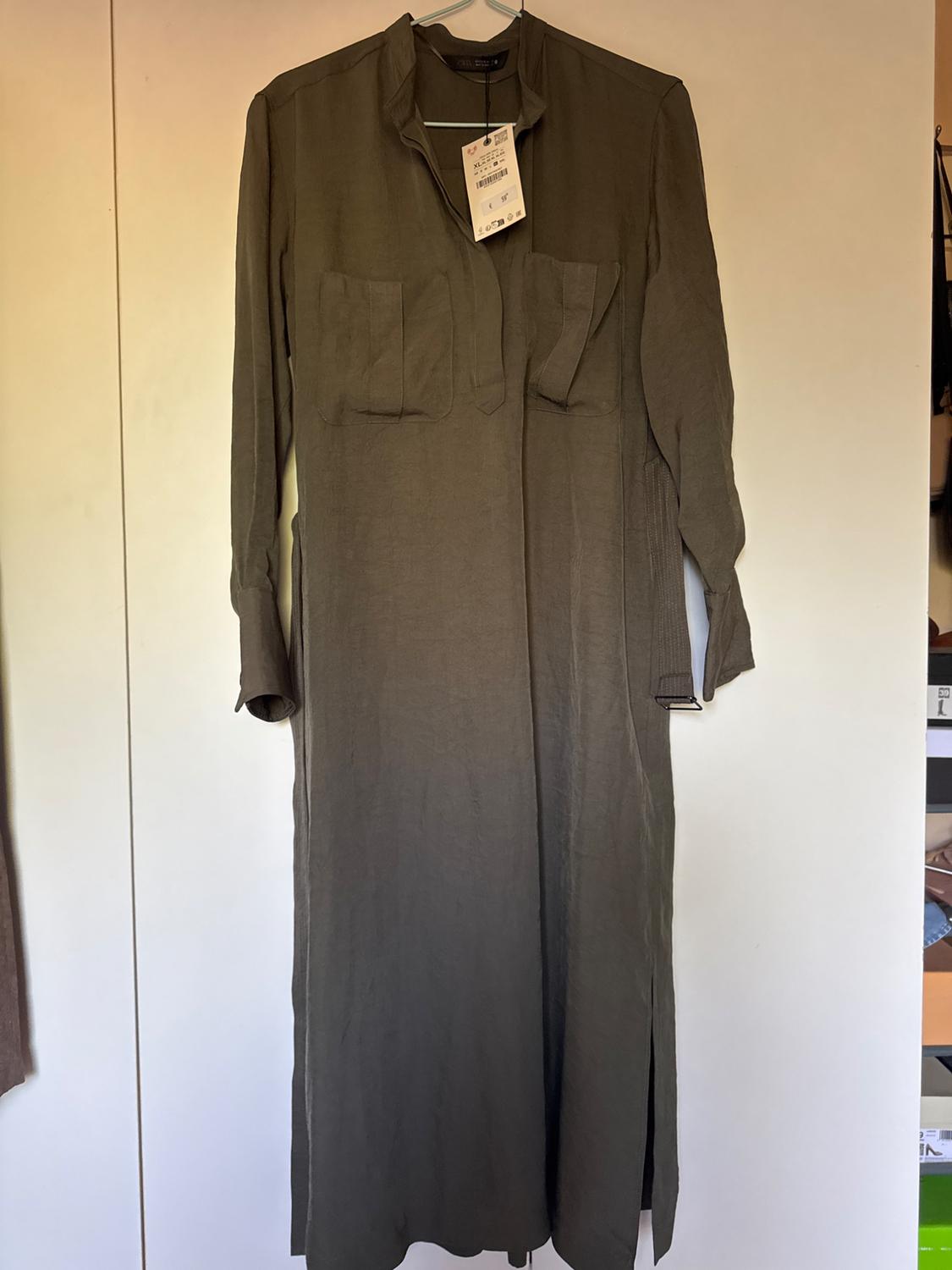 Long-sleeved maxi dress in brown hanging on a clothes hanger, with two front pockets and visible label.