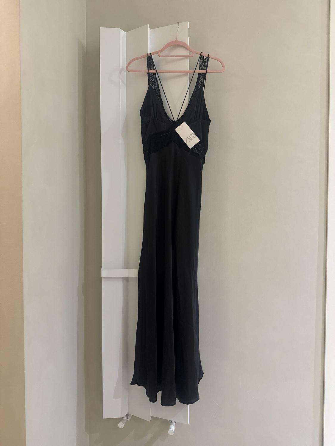 Μαύρο lingerie φόρεμα με δαντέλα κρεμασμένο σε ροζ κρεμάστρα πάνω σε λευκό πλαίσιο. Ετικέτα με το κείμενο ZAR.