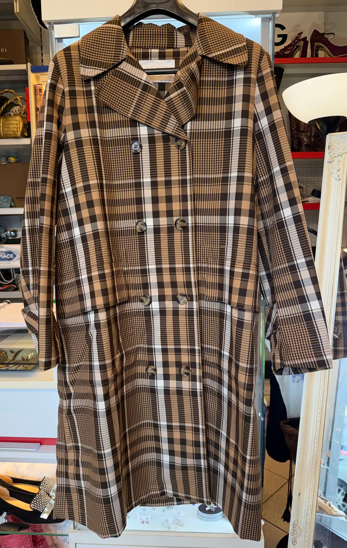 Brown and black checked coat hanging on a hanger, with a shop background showing shelves and shoes.