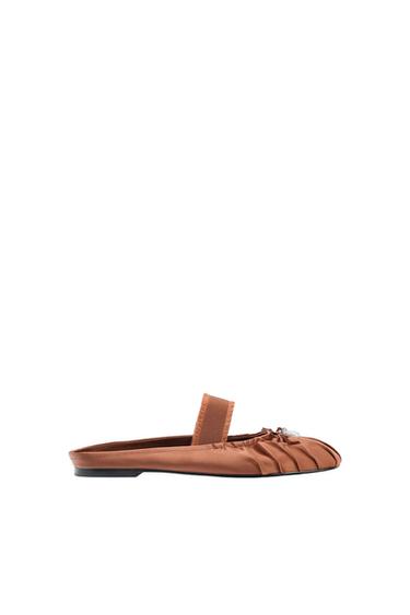 Brown flat shoe with pleated design and bow detail on top, on a white background.