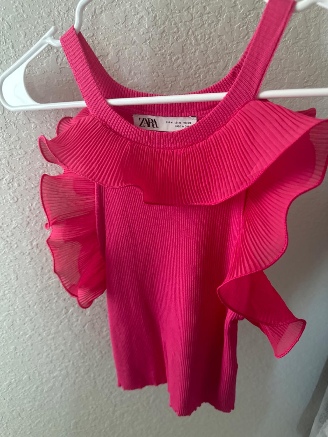 Detail of pink blouse with pleated frills on the neck and sleeves.