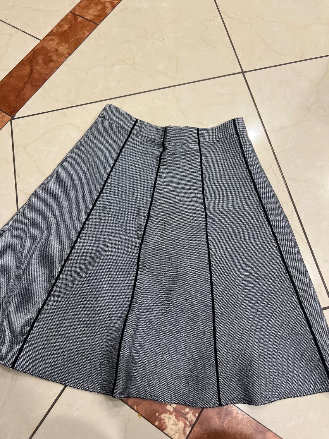 Grey skirt with black vertical stripes on a beige and brown tiled floor.