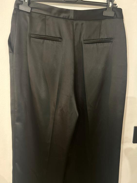 Black dress trousers hanging on a hanger, with jetted back pockets and a smooth, elegant finish.