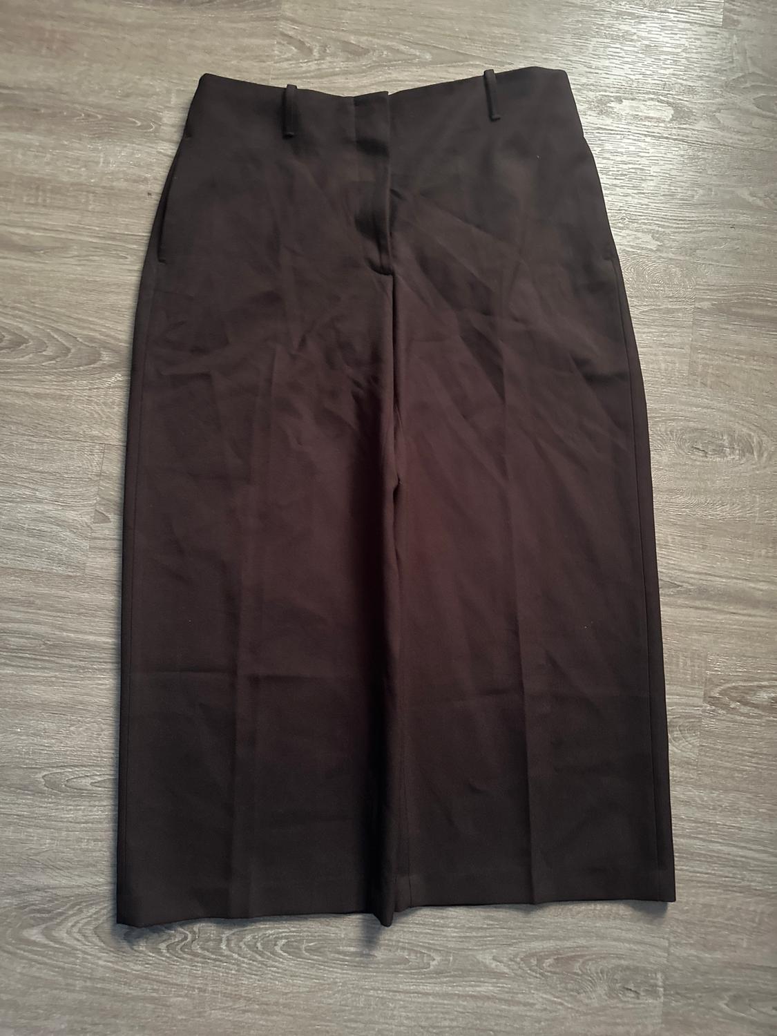 Black wide-leg pants on a light wood floor. No visible details or embellishments.