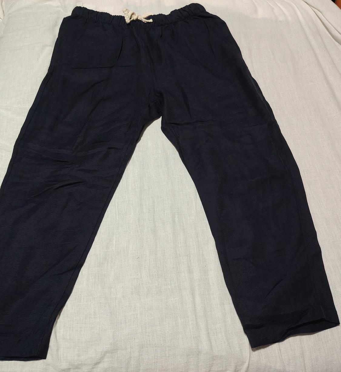 Dark trousers with an elasticated waistband and white drawstring, laid out on a light surface.