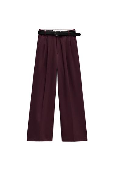 Front view of burgundy trousers with black belt and front pleats.