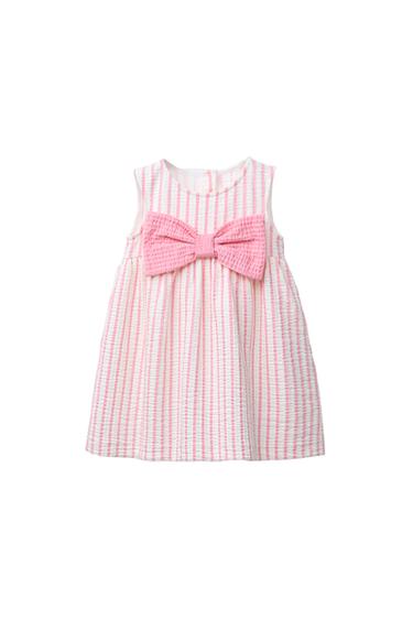 Front view of a child's pink striped dress with a large bow on the chest.