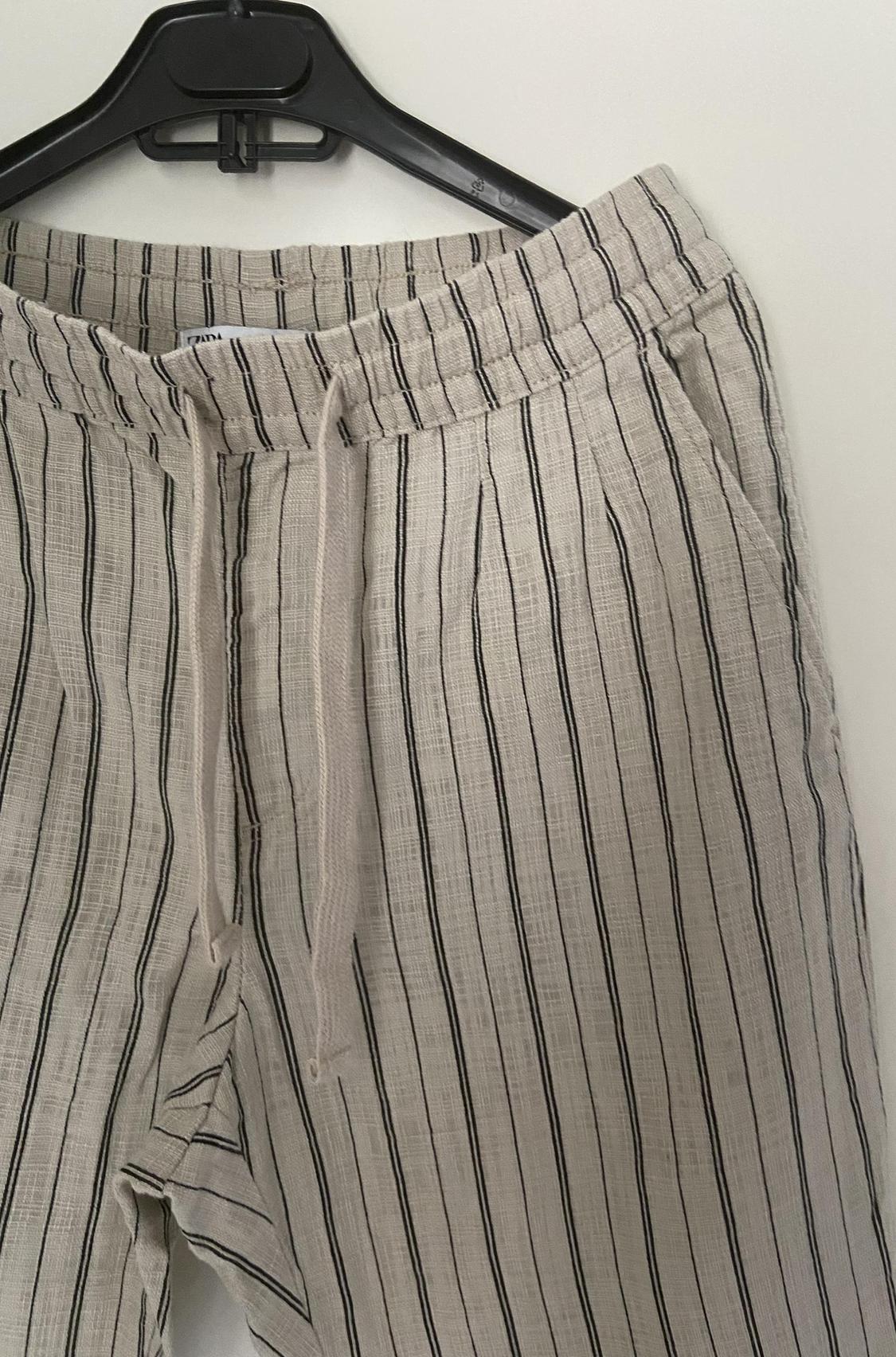 Close-up of vertically striped trousers with an elasticated waist and side pockets