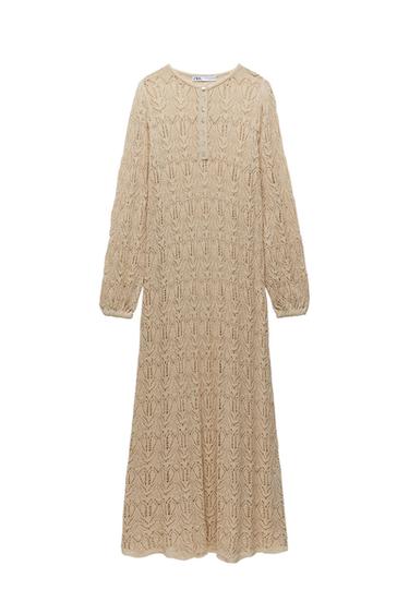 Front view of a long beige dress with lace texture and button fastening at the chest.