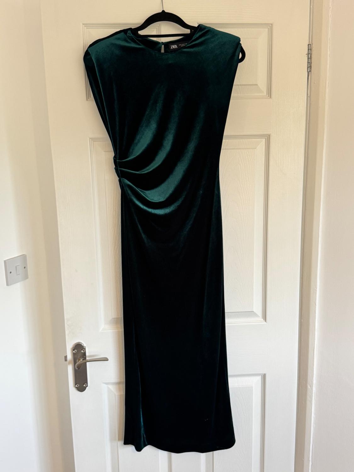 Front view of a dark green long dress with pleats on the side.