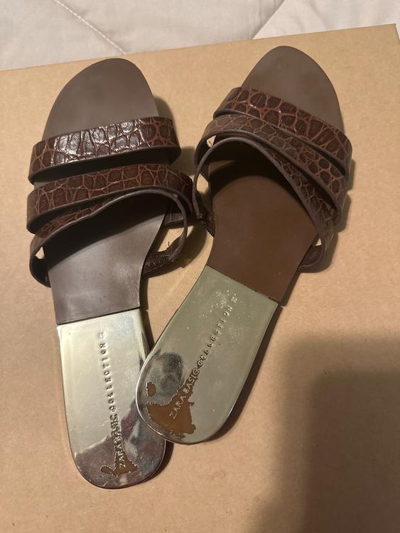 Brown sandals with textured straps on a box. The metallic sole shows the text "ZARA BASIC COLLECTION".
