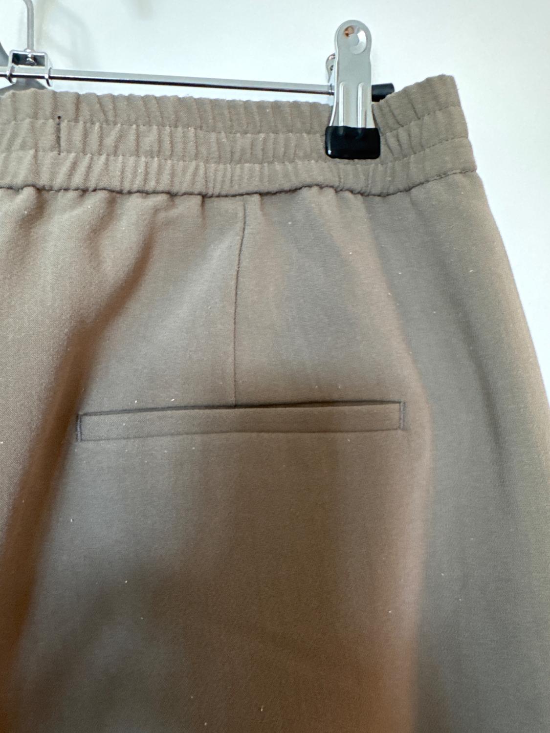 Beige trousers hanging on a hanger, showing the back with a pocket and elasticated waist. White background.