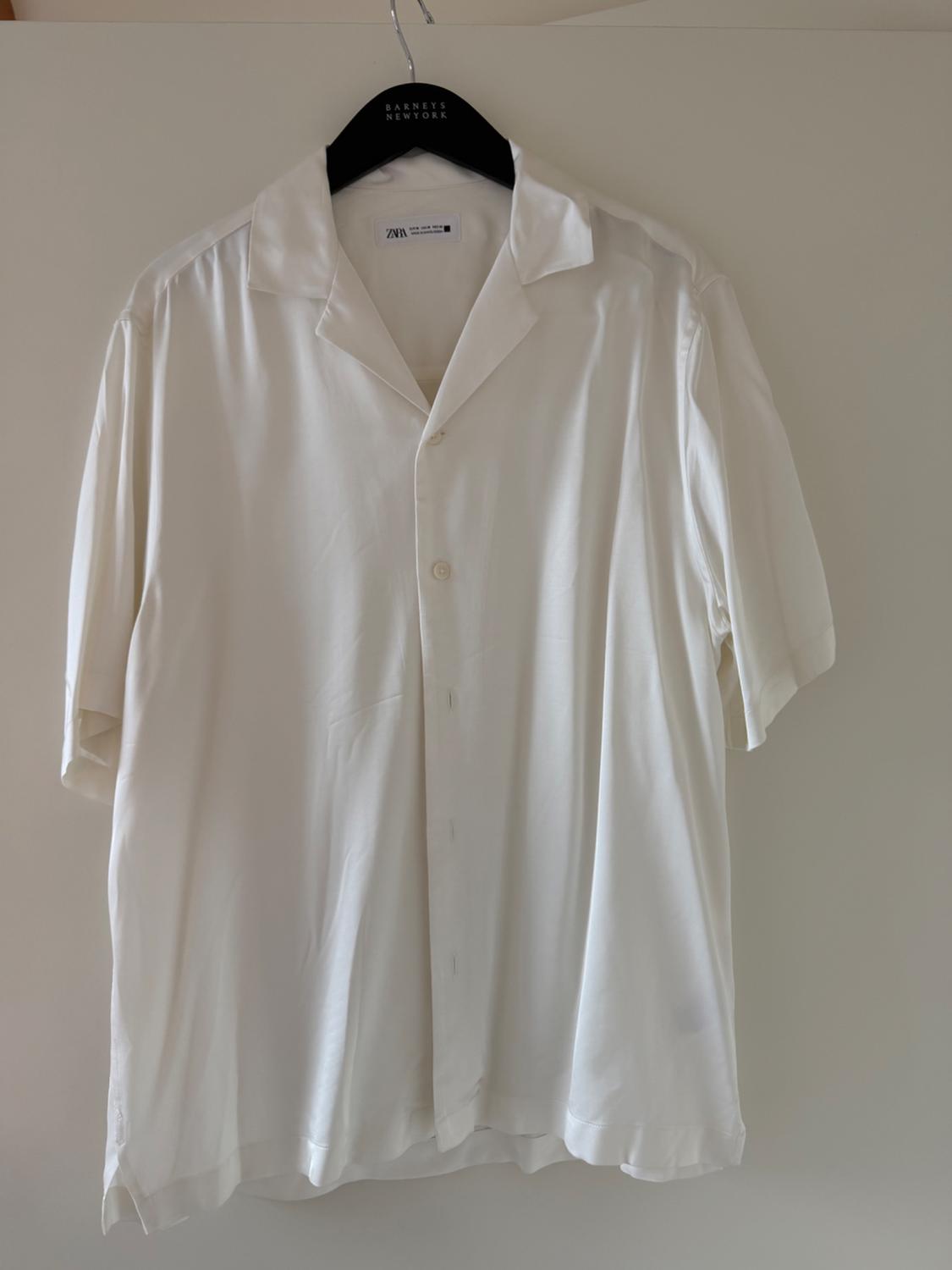White short-sleeved shirt hanging on a black hanger with the label "Barnets New York". Plain white background.