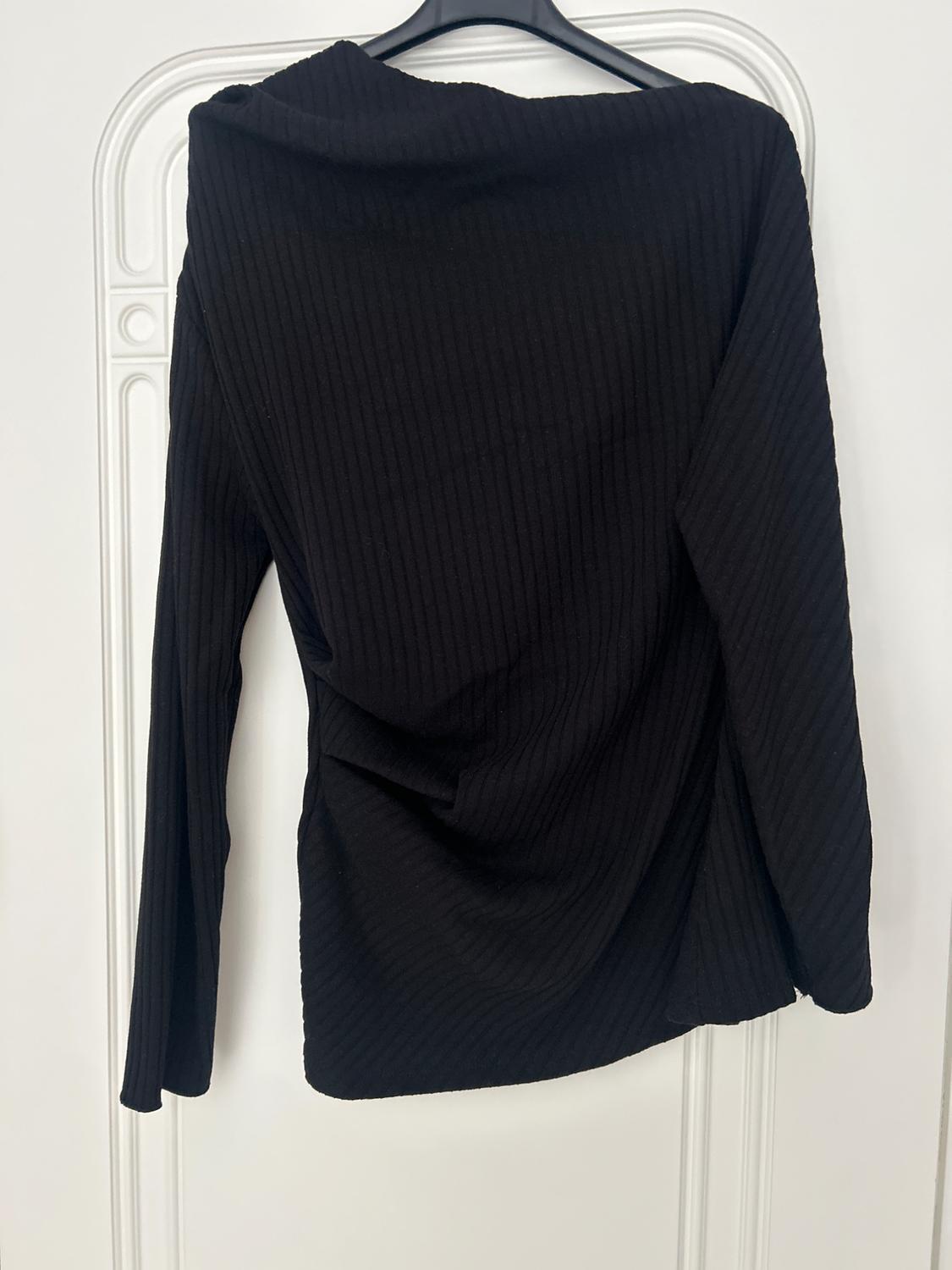 Black long-sleeved ribbed top, hanging on a hanger against a white background with decorative details.