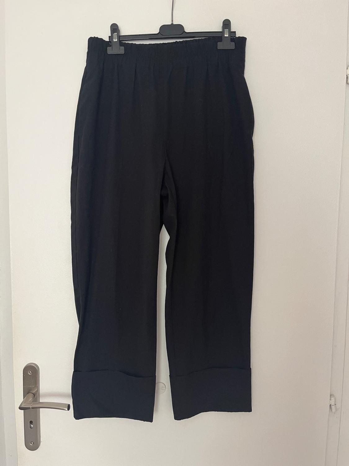 Front view of black trousers with elasticated waist and wide hem.