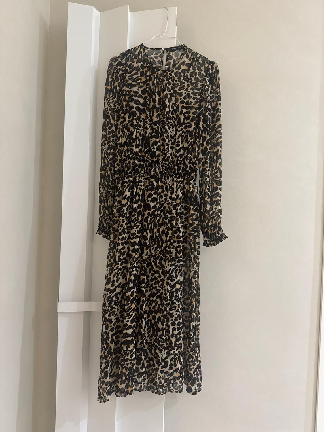 Μακρύ φόρεμα με animal print, μακριά μανίκια, ελαστική μέση και στρογγυλή λαιμόκοψη, κρεμασμένο σε κρεμάστρα σε λευκό φόντο.