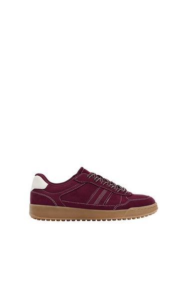 Burgundy trainer, profile view, with white stitching, laces, white heel and brown rubber sole on a white background.