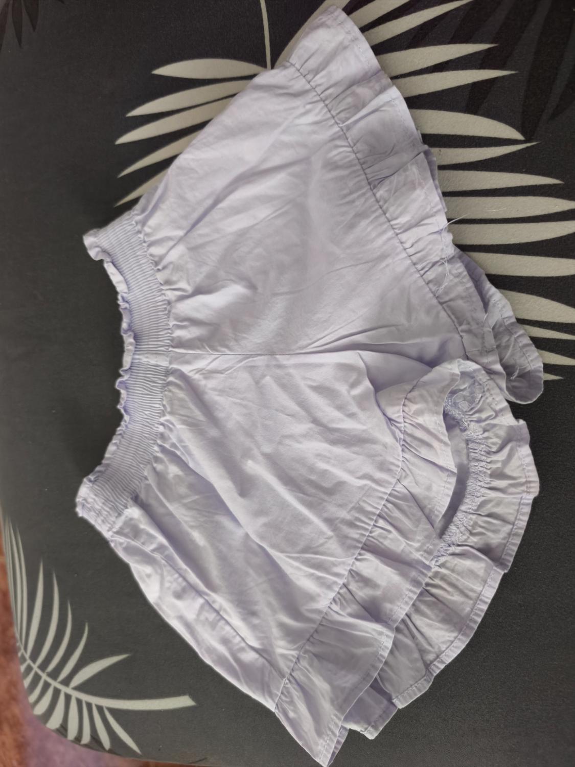 White frilly shorts on a dark background with a light-toned leaf design.