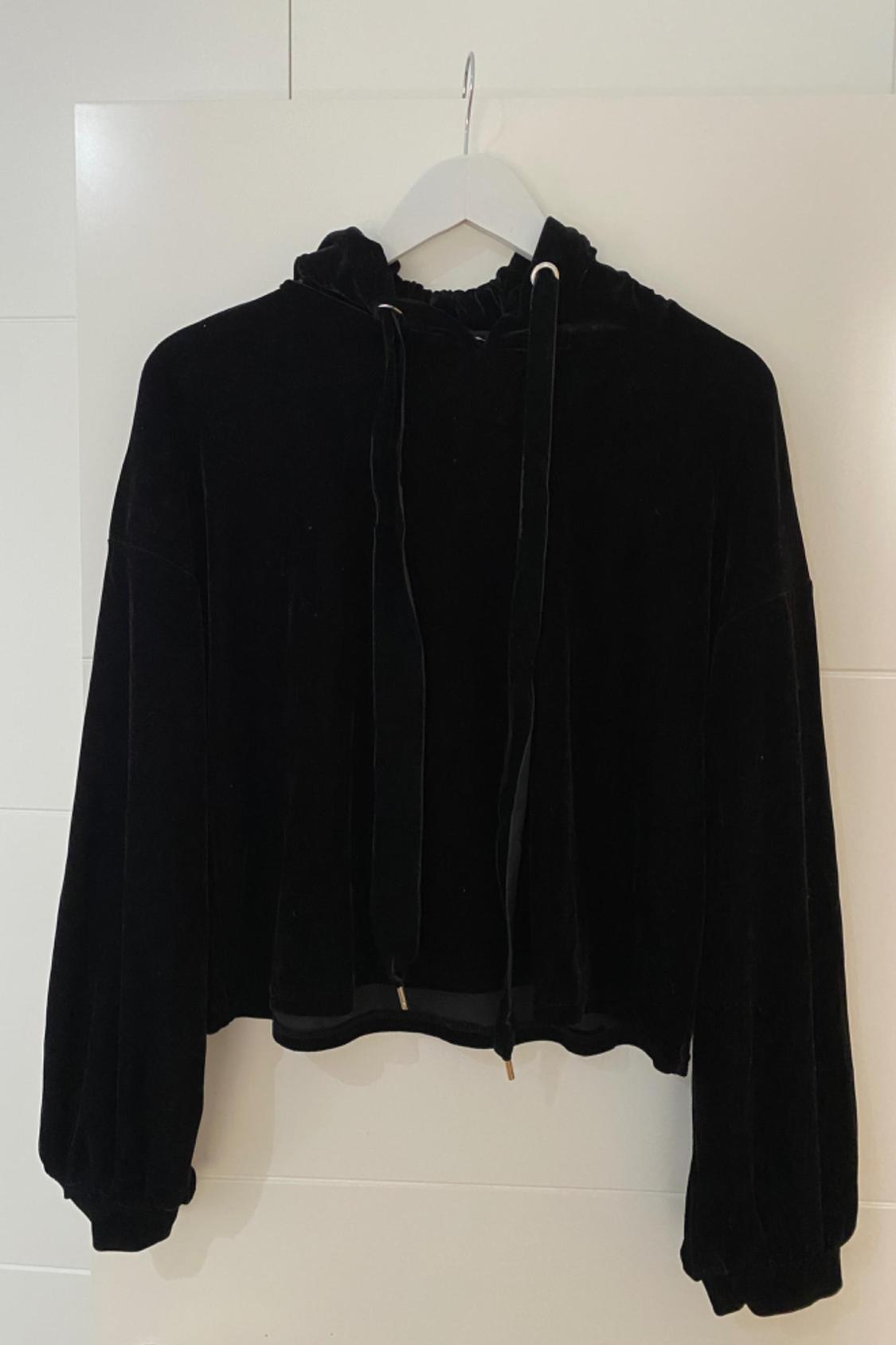 Front view of a black hooded sweatshirt with long drawstrings.
