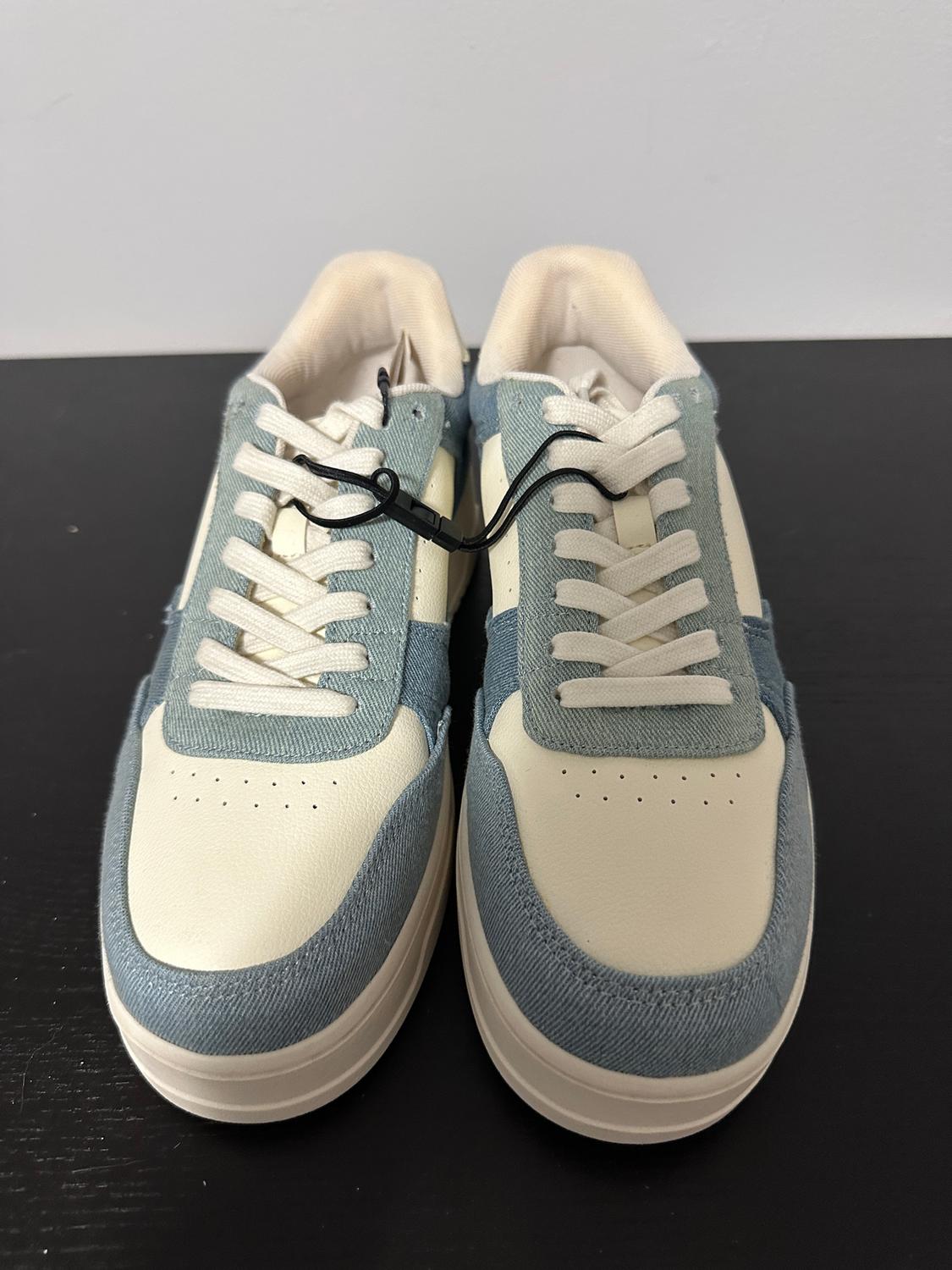 White and blue trainers with white laces on a black background.