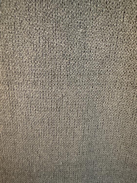 Close-up of a gray fabric texture, showing a tight and uniform knit pattern.