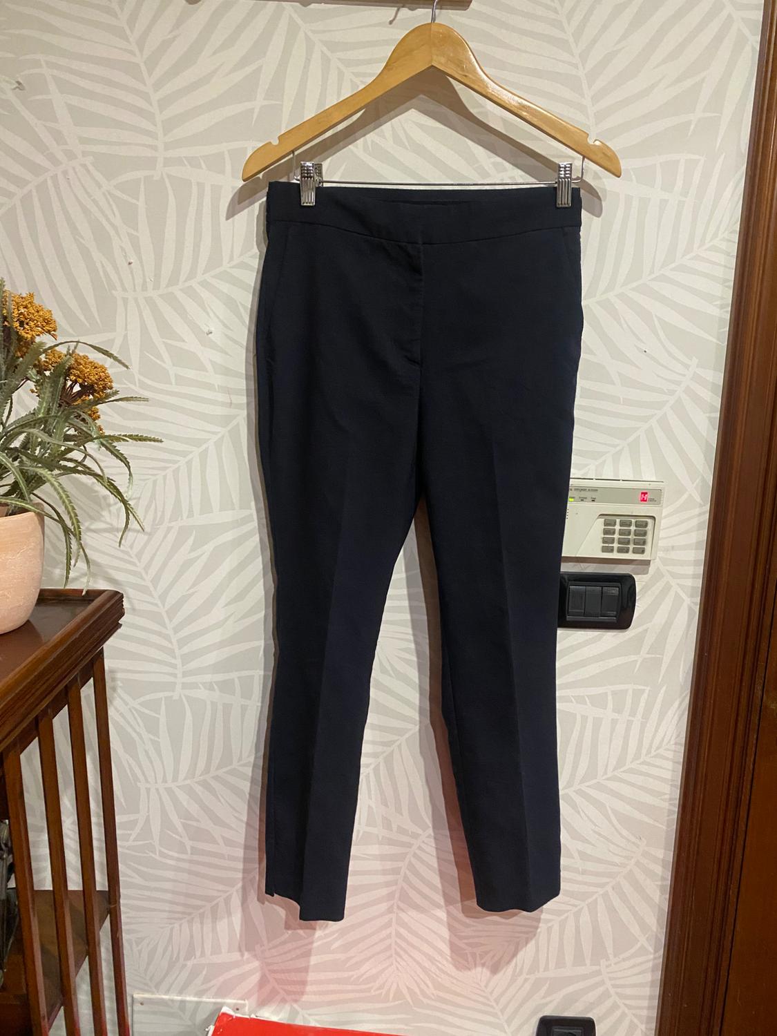 Front view of black trousers hanging on a hanger.
