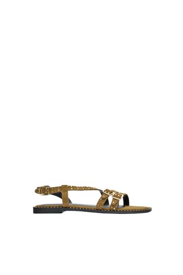 Khaki green flat sandal with straps, small studs and gold buckles on a white background.