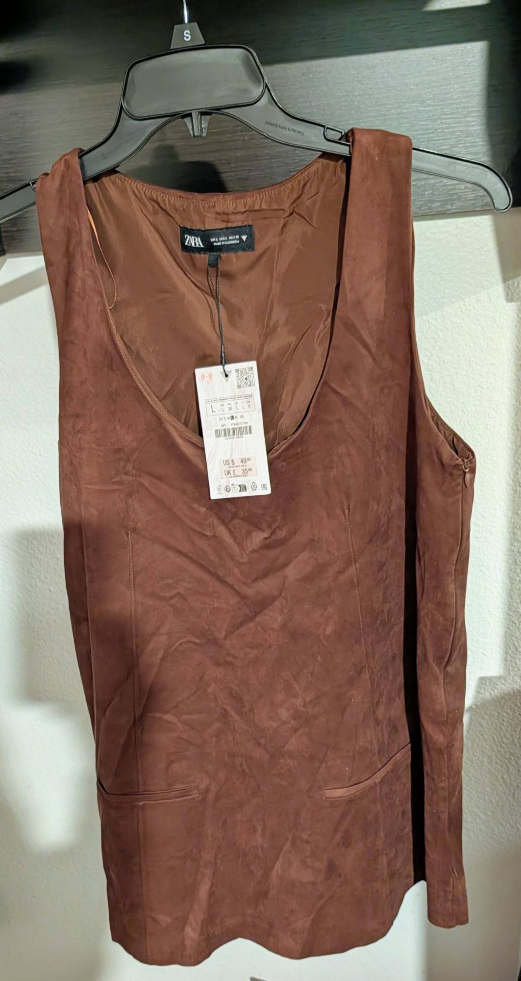 Brown sleeveless top hanging on a black hanger with a visible price tag. Inside tag reads "Zara."