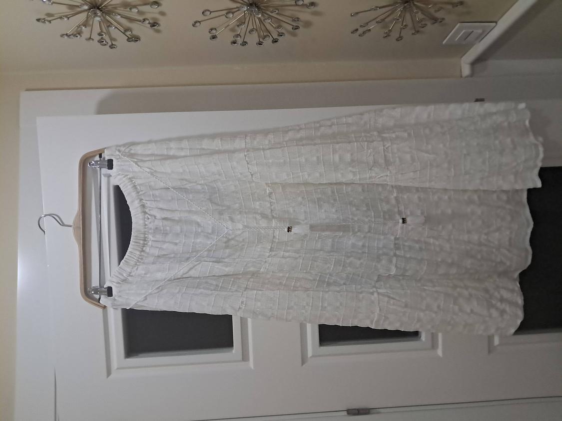 Textured white skirt hanging on a wooden hanger in front of a white door, with metallic wall decor.
