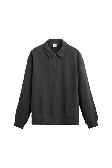 Black long-sleeved sweatshirt with a polo collar and button fastening. Visible label on the inside of the neck. White background.