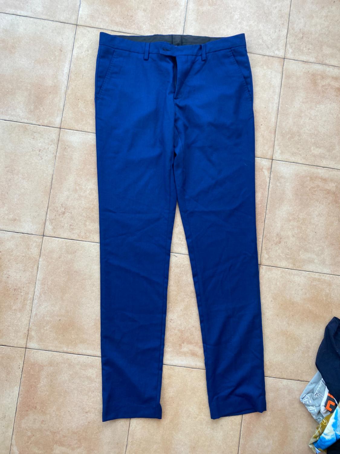 Navy trousers on a beige tiled floor. Part of some colourful clothing visible in the bottom right corner.