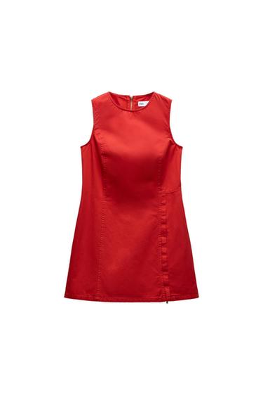 Short red sleeveless dress with a crew neck. It features decorative stitching and a zipper detail on the hem, against a white background.