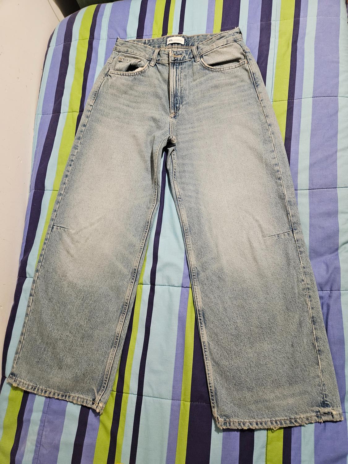 Front view of light blue jeans with side pockets and button fastening.