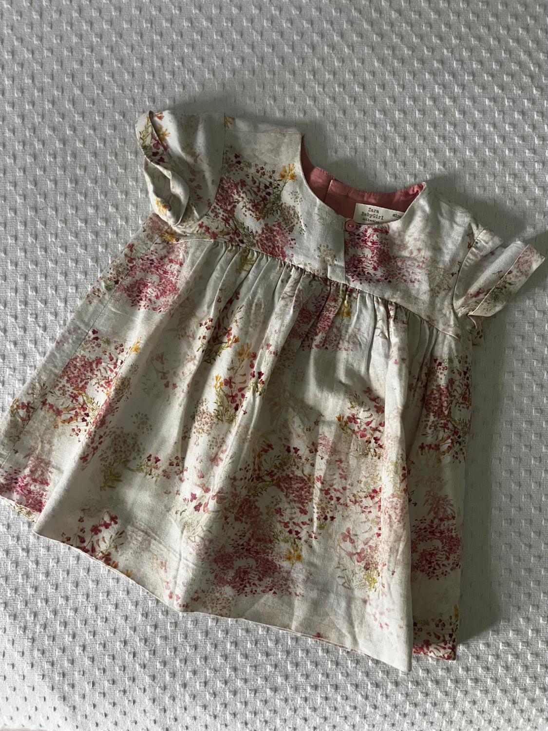 Front view of a child's dress with a floral print in pink and yellow tones, short puffed sleeves.