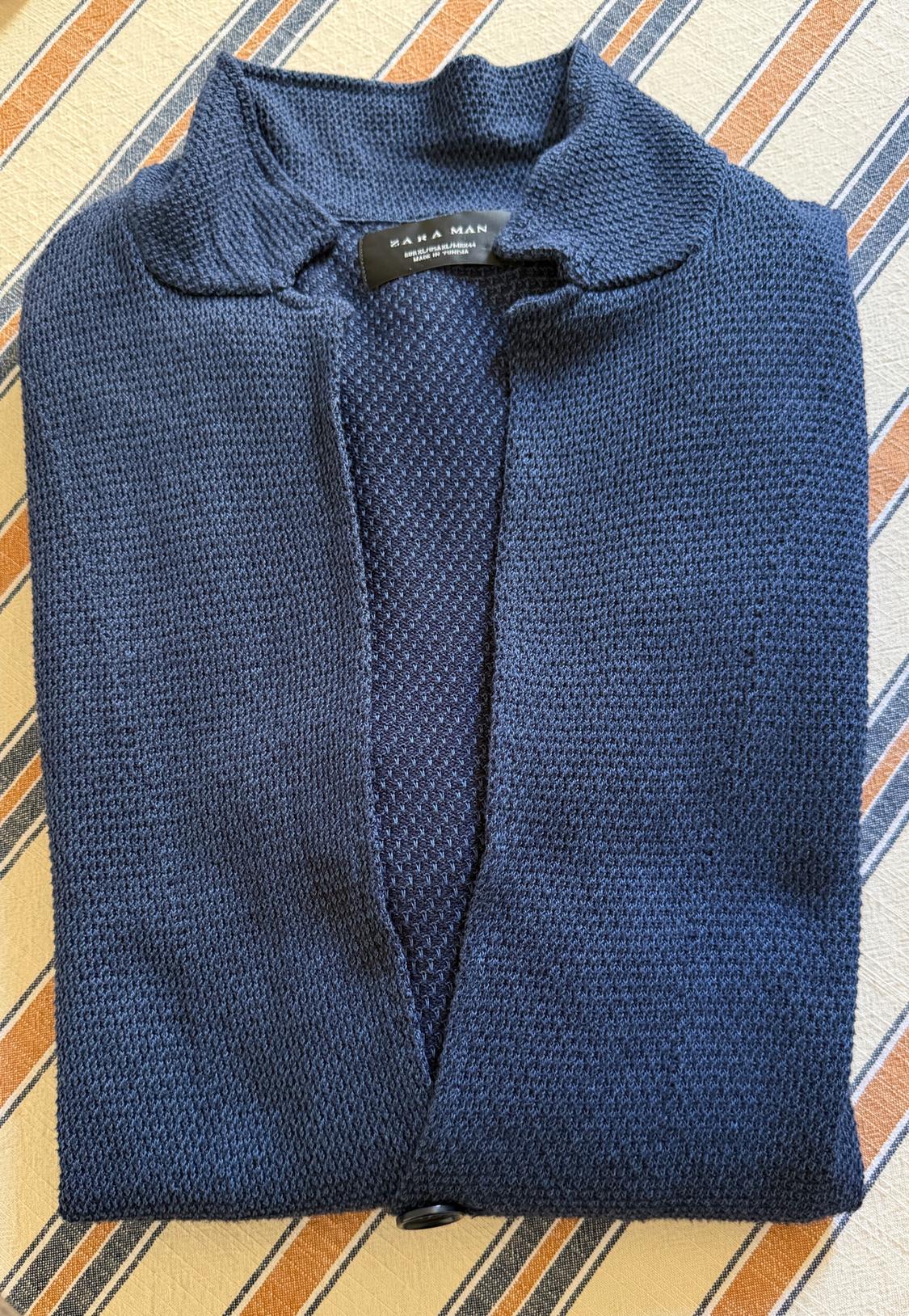 Dark blue knit polo shirt with a collar, folded over striped fabric. Label with the text ZARA MAN. Casual and relaxed style.
