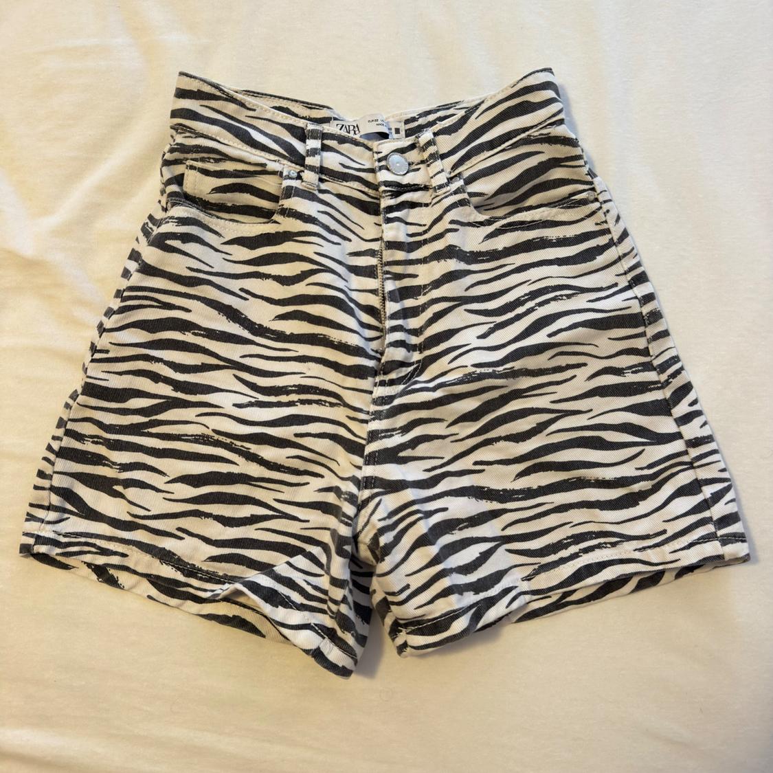Black and white zebra-print denim shorts, set against a light fabric background. Visible ZARA label.