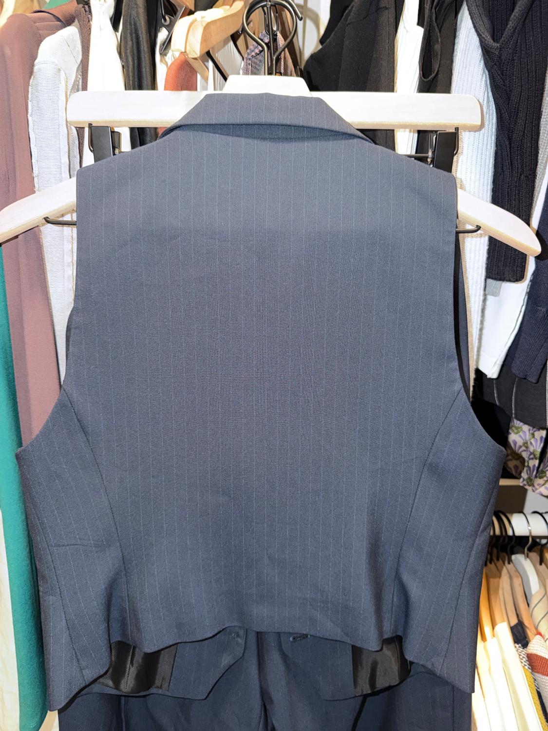Dark blue pinstripe vest hanging on a coat rack, surrounded by various colored garments in a closet.