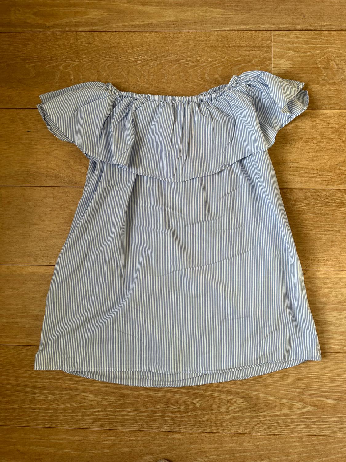 Front view of a blue and white striped off-the-shoulder dress with ruffles on the bust.