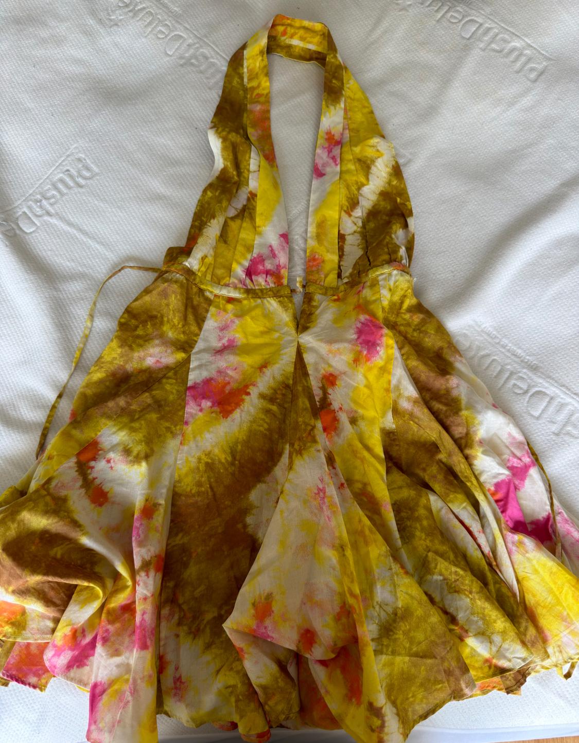 Halterneck dress with a V-neckline, yellow, brown, and pink tie-dye print on a white background with PlushDeluxe text. Relaxed fit.
