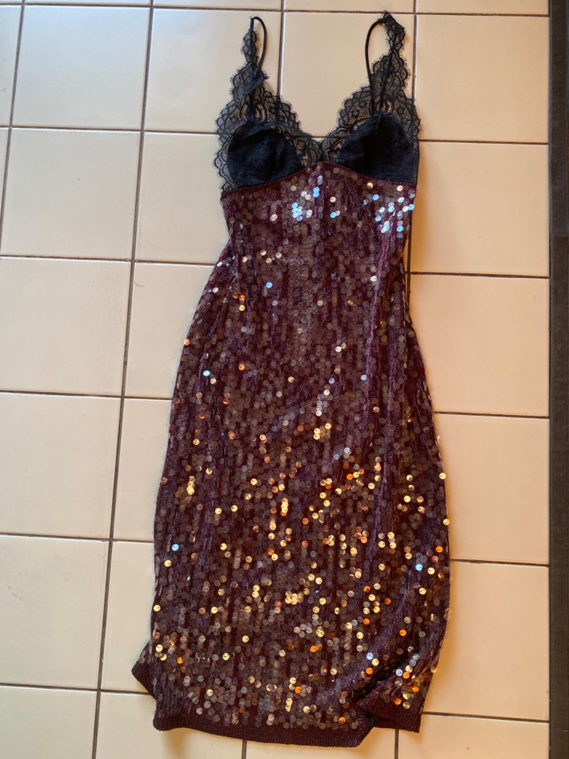 Maroon sequinned slip dress with a black lace bust, photographed from above on a light tiled floor.