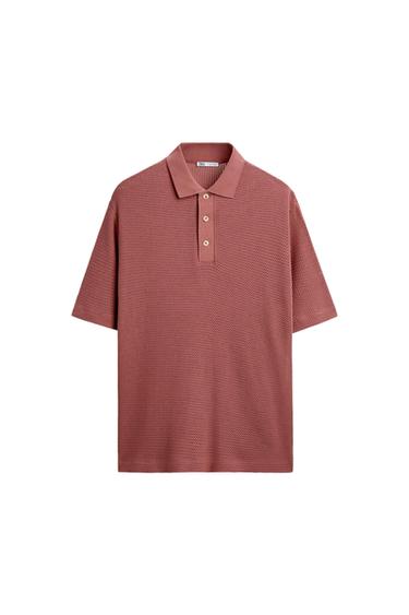 Dark pink short-sleeved polo shirt in textured fabric, with a classic collar and three front buttons, on a white background.