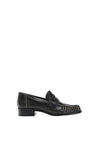 Black textured leather loafer, with a low sole and visible stitching detail, on a white background.