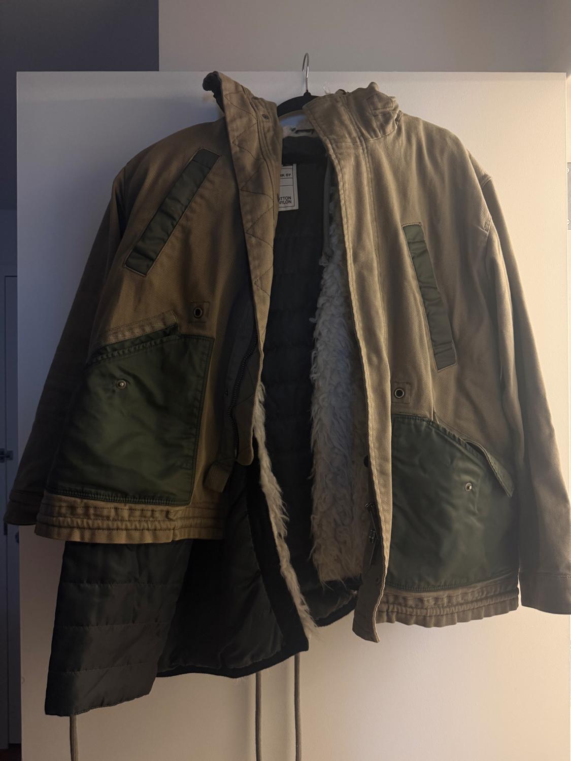 Jacket hanging on a hanger, with a brown exterior and green pockets. Visible white lining interior. White background.
