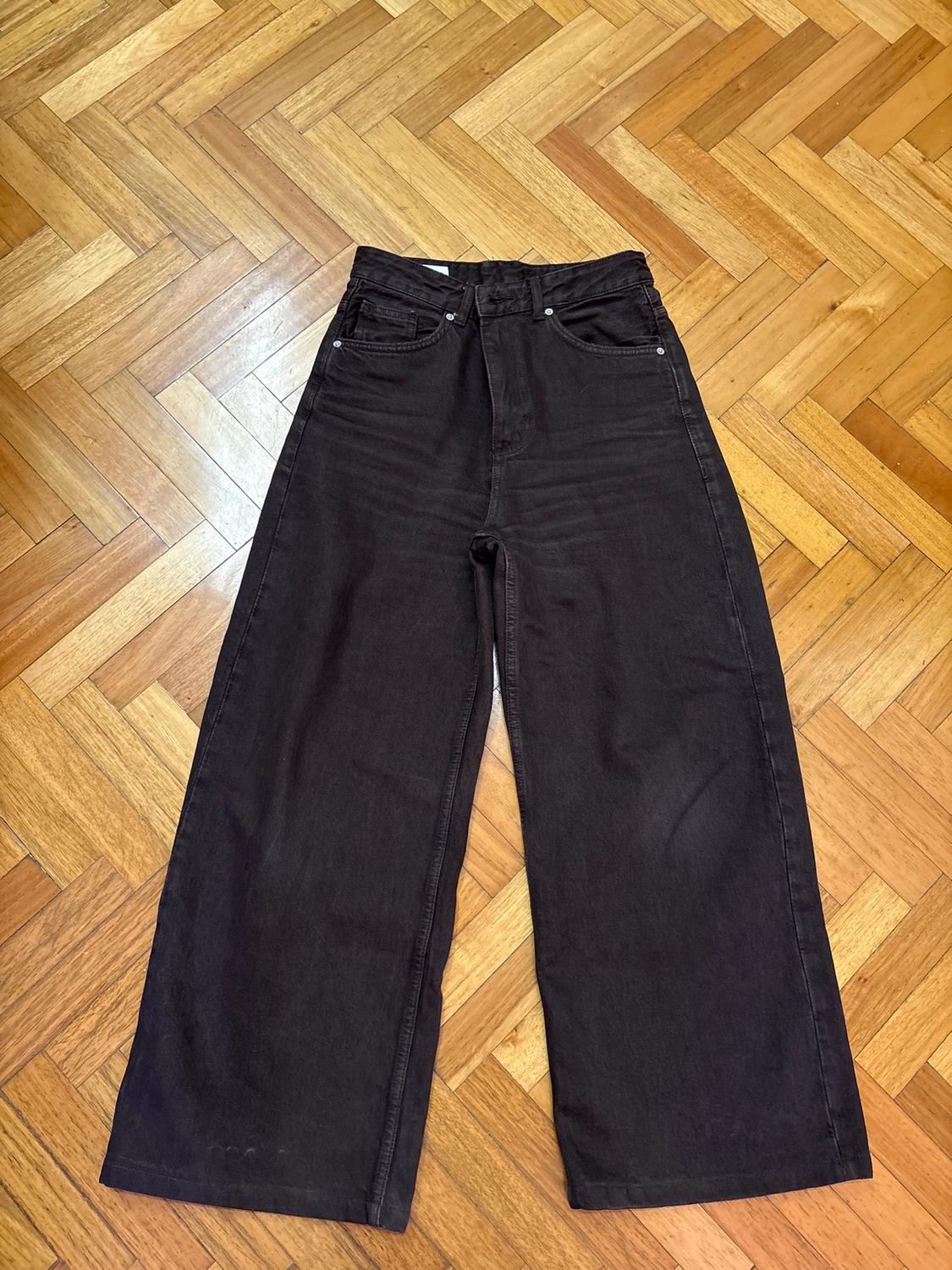 Black wide-leg jeans placed on a herringbone wooden floor.