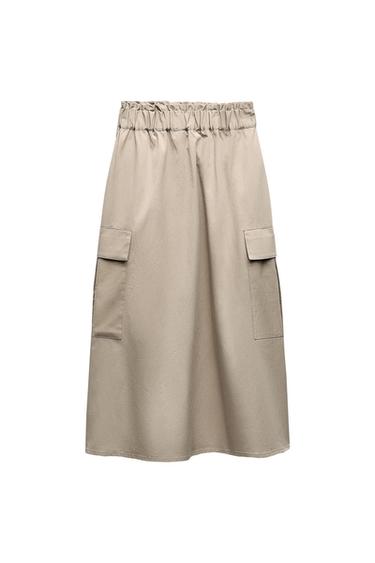 Beige midi skirt with a gathered elasticated waistband and side cargo flap pockets against a white background.