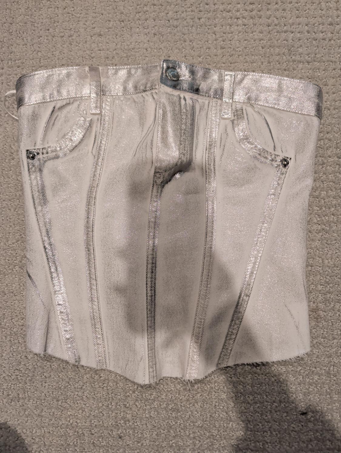 Silver corset with denim design, pockets and belt loops, on a beige rug.