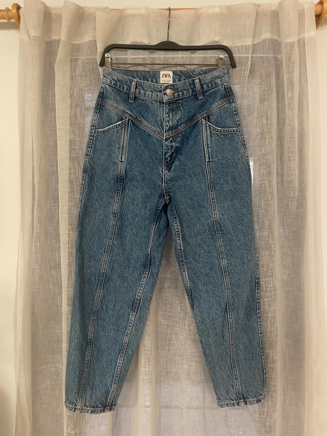 Front view of blue jeans with visible seams and slanted front pockets.