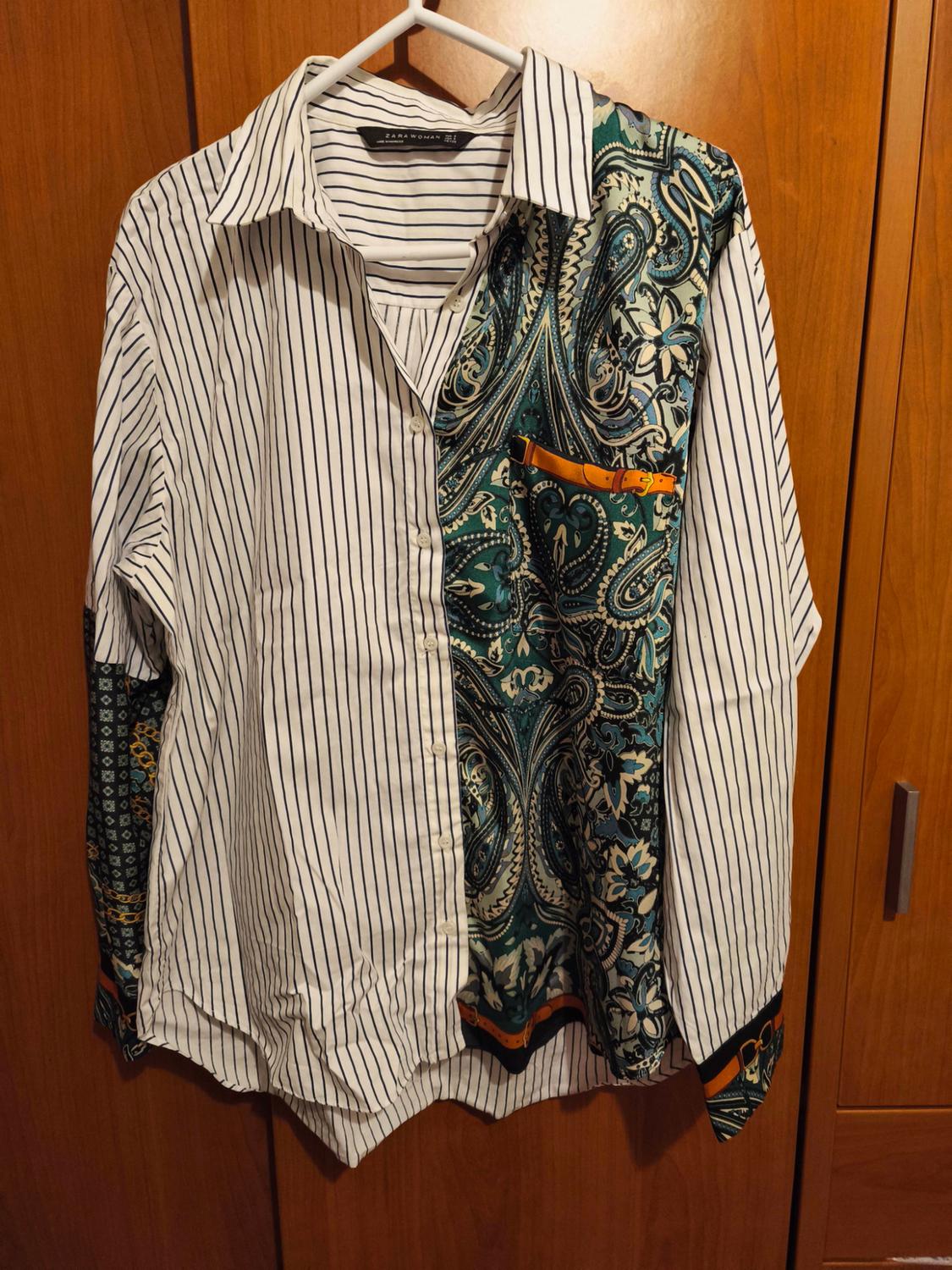 Shirt hanging on a hanger, with a black and white striped design on the left and a green and blue paisley print on the right.
