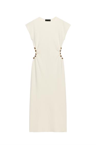 Front view of a raw-edge dress with a round neck, sleeveless, and side cut-outs at the waist with ball detailing.
