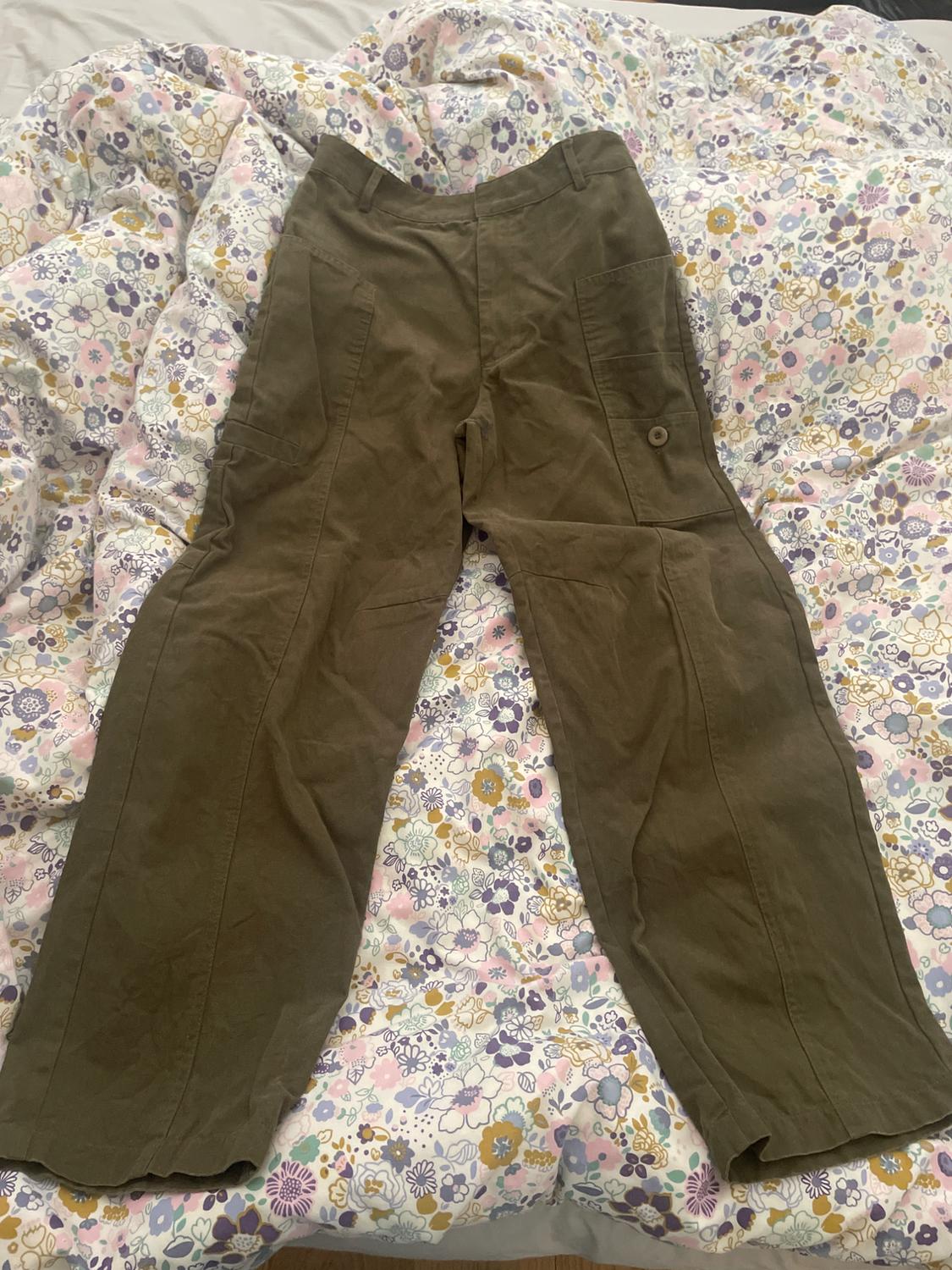 Green cargo trousers on a floral pastel-patterned bedspread.
